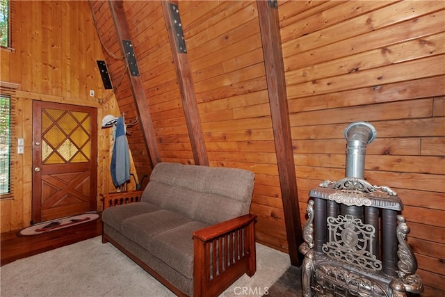 sitting room with a wood stove, wood walls, and carpet