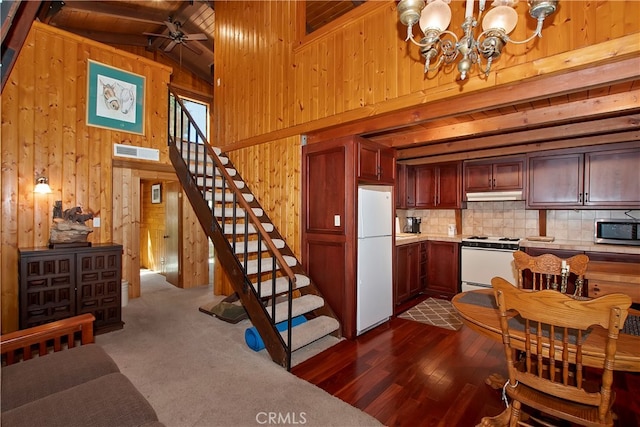 kitchen with tasteful backsplash, white appliances, beam ceiling, wooden walls, and dark hardwood / wood-style floors