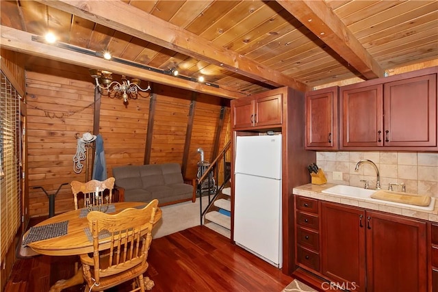 kitchen featuring backsplash, dark wood-style flooring, beam ceiling, wooden ceiling, and freestanding refrigerator