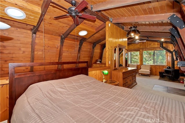 bedroom with vaulted ceiling with beams, a wood stove, wooden walls, and wooden ceiling