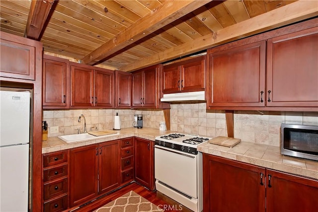 kitchen featuring beam ceiling, a sink, white appliances, tile countertops, and wood ceiling