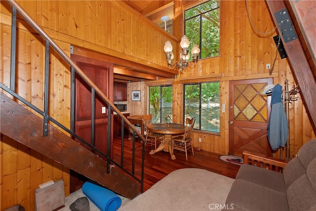 dining room featuring wood-type flooring, an inviting chandelier, wood walls, and a towering ceiling