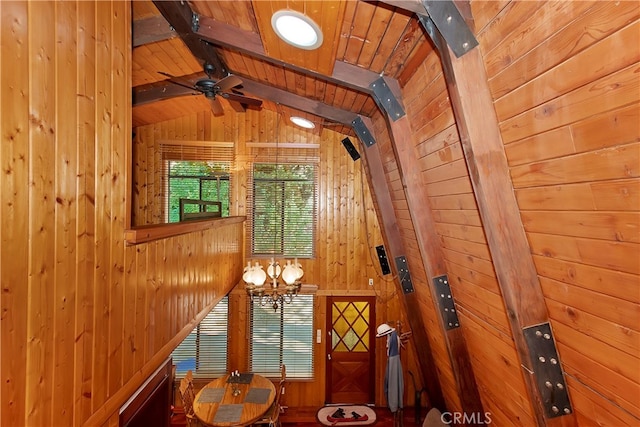 interior space with wood ceiling, wood walls, beamed ceiling, and ceiling fan with notable chandelier