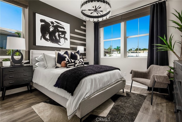 bedroom featuring hardwood / wood-style flooring, a chandelier, and multiple windows