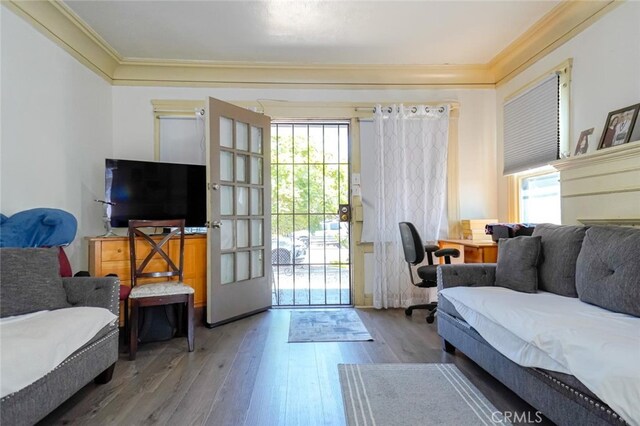 living room featuring wood-type flooring, crown molding, and a wealth of natural light