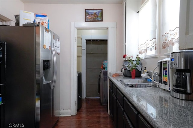 kitchen featuring light stone countertops, washer / dryer, stainless steel refrigerator with ice dispenser, dark hardwood / wood-style floors, and sink