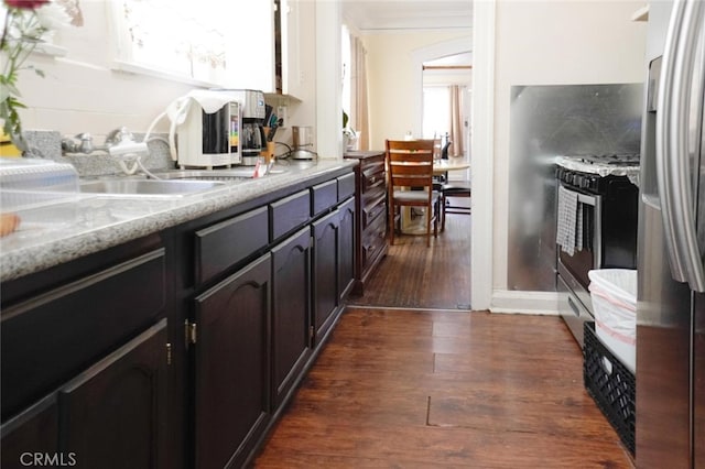 kitchen featuring stainless steel appliances, light stone counters, dark wood-type flooring, and sink