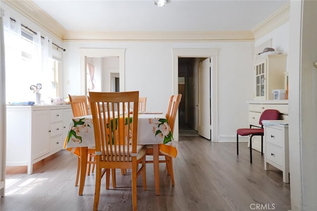 dining space with ornamental molding and light hardwood / wood-style floors