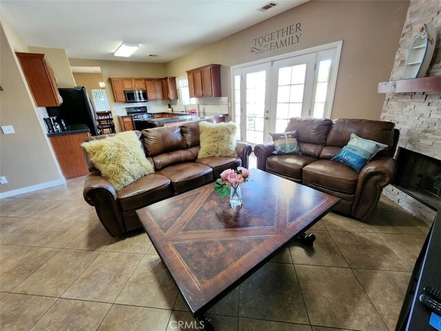 tiled living room with french doors, a fireplace, and sink