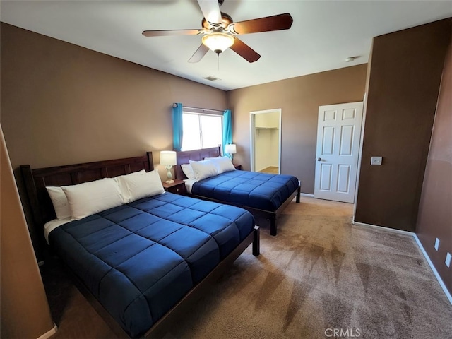 carpeted bedroom featuring ceiling fan and a walk in closet