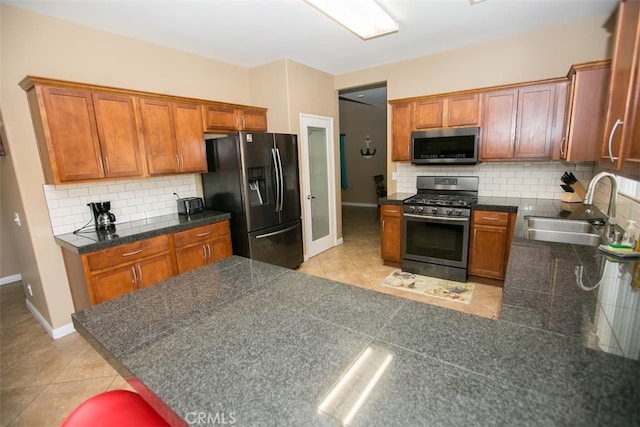 kitchen with light tile patterned flooring, tasteful backsplash, kitchen peninsula, stainless steel appliances, and sink