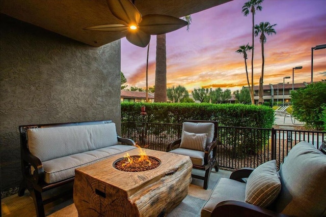 patio terrace at dusk with an outdoor living space with a fire pit and ceiling fan