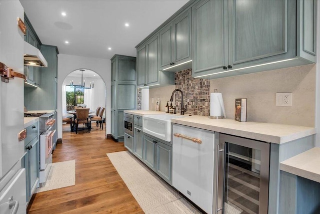 kitchen featuring sink, wine cooler, backsplash, high end stainless steel range, and light hardwood / wood-style flooring