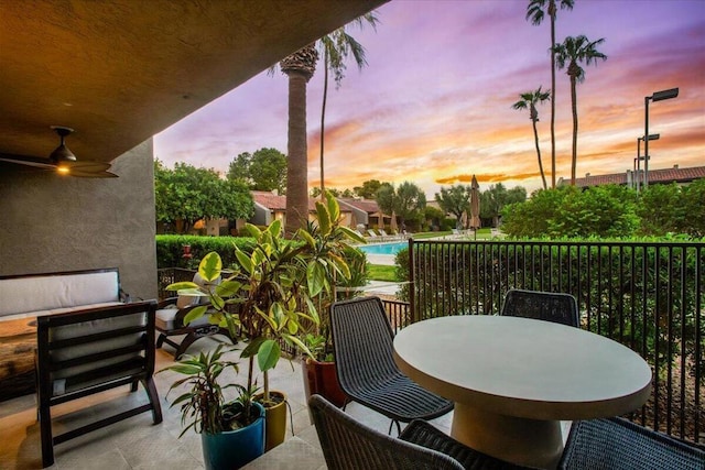 balcony at dusk featuring ceiling fan