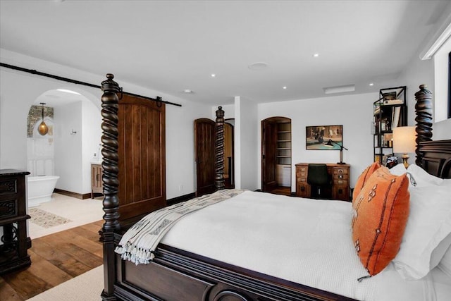 bedroom featuring wood-type flooring and a barn door