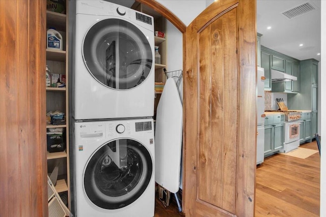 washroom featuring stacked washer / drying machine and light hardwood / wood-style floors