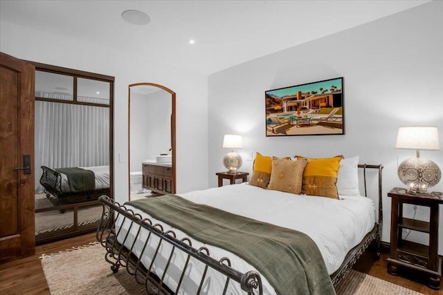 bedroom with connected bathroom and dark hardwood / wood-style flooring