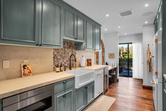 kitchen with sink, stainless steel microwave, beverage cooler, light hardwood / wood-style floors, and backsplash