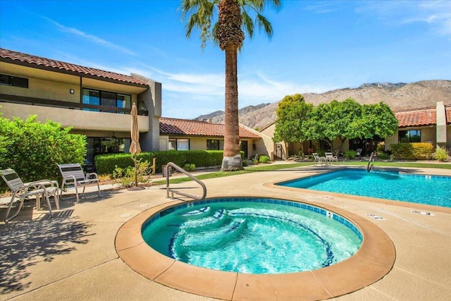 view of swimming pool with a community hot tub, a mountain view, and a patio