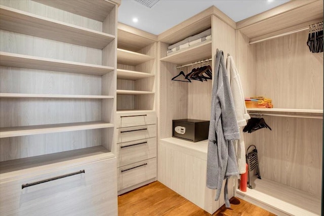 walk in closet with light hardwood / wood-style floors