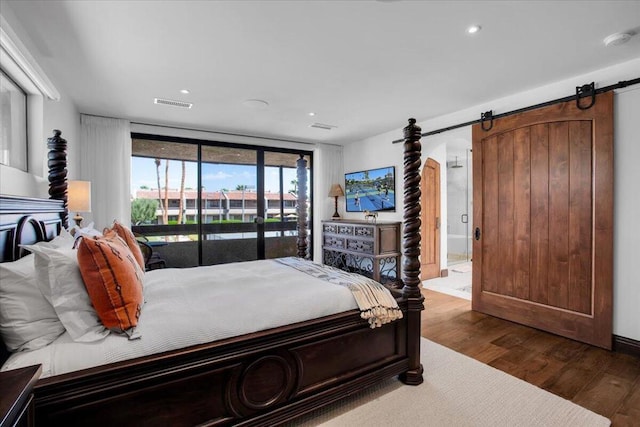 bedroom featuring access to exterior, hardwood / wood-style flooring, a wall of windows, and a barn door