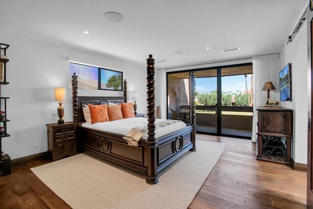 bedroom with wood-type flooring, floor to ceiling windows, and access to exterior