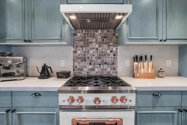 kitchen with premium range hood, stainless steel gas range, blue cabinetry, and tasteful backsplash