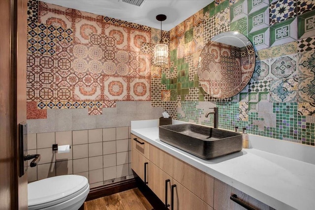 bathroom featuring tile walls, vanity, hardwood / wood-style floors, and toilet