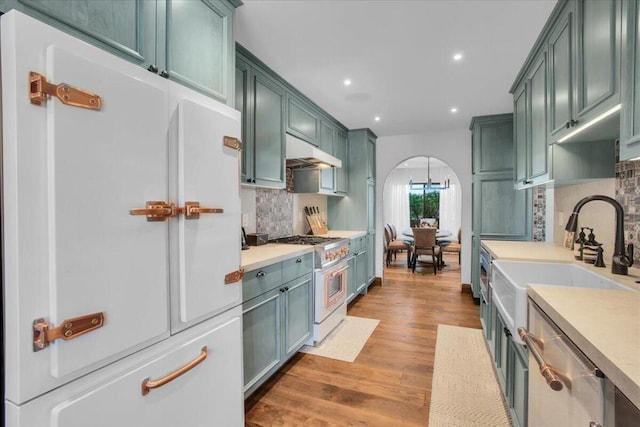 kitchen featuring sink, decorative backsplash, green cabinets, white appliances, and light hardwood / wood-style flooring