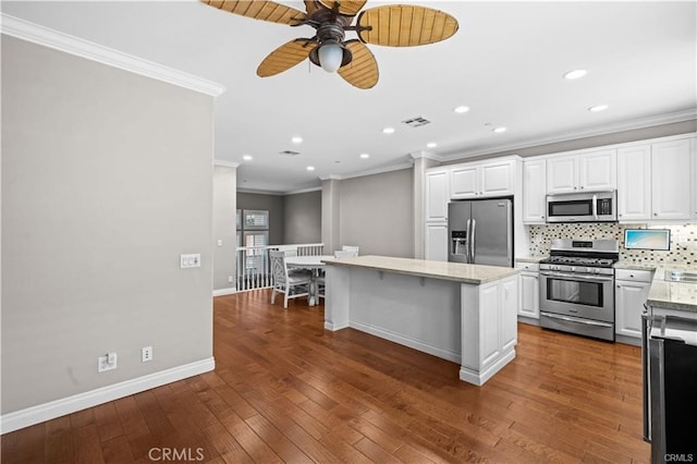 kitchen featuring dark wood-type flooring, appliances with stainless steel finishes, white cabinetry, and a kitchen island