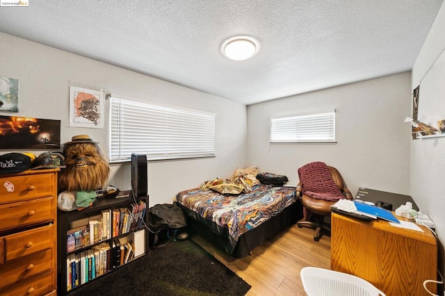 bedroom with a textured ceiling and light hardwood / wood-style floors