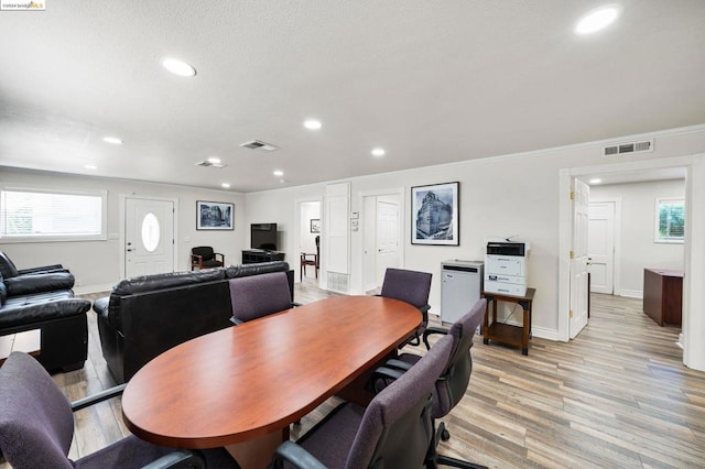 dining area with light wood-type flooring and ornamental molding