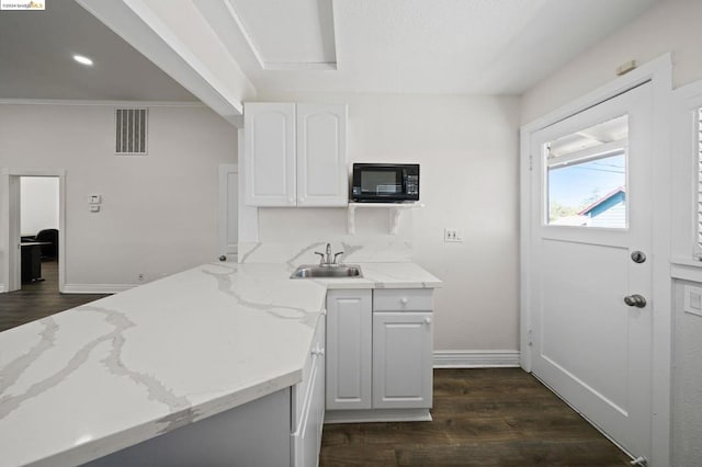 kitchen with dark wood-type flooring, white cabinetry, sink, and light stone countertops