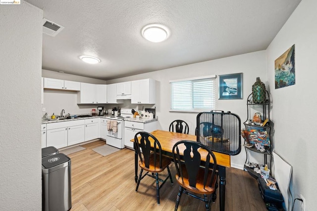 kitchen featuring a textured ceiling, light hardwood / wood-style flooring, sink, white electric stove, and white cabinets