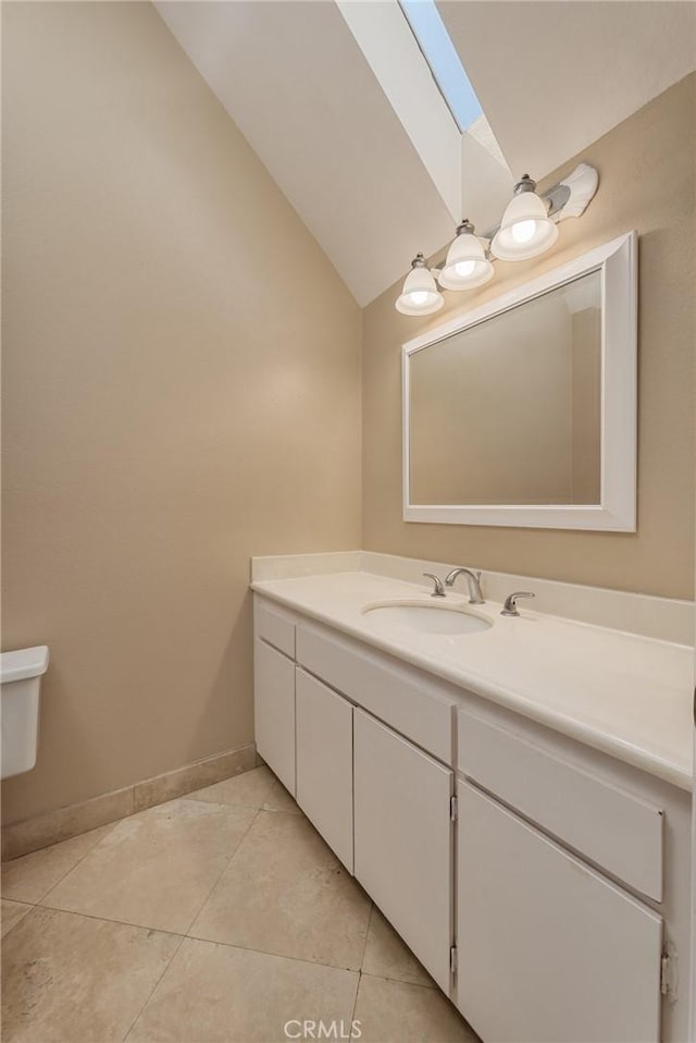 bathroom with tile patterned floors, vaulted ceiling with skylight, and vanity