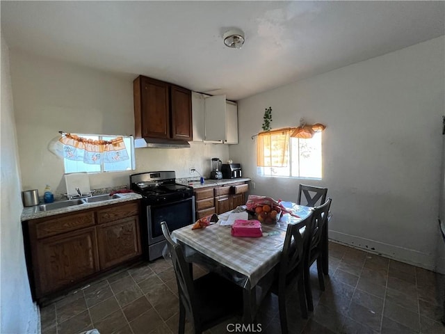 kitchen with dark brown cabinets, stainless steel range with gas cooktop, and sink