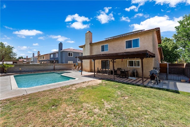 back of house with a fenced in pool, a patio area, and a lawn