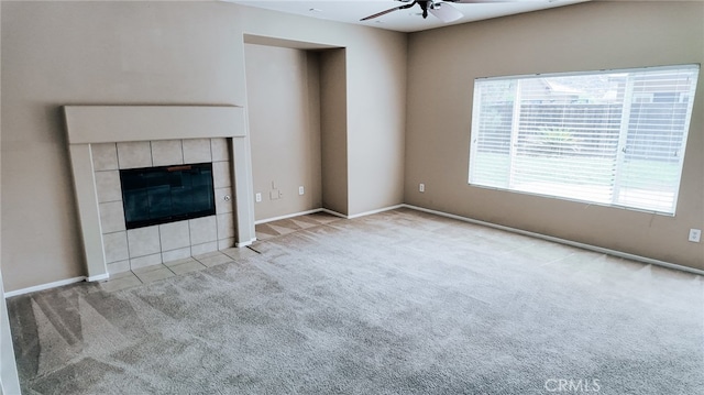 unfurnished living room with ceiling fan, light colored carpet, and a tile fireplace