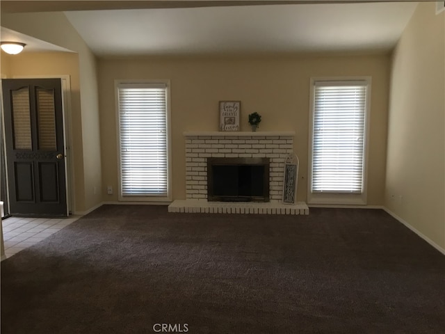 unfurnished living room with a brick fireplace, lofted ceiling, and light colored carpet