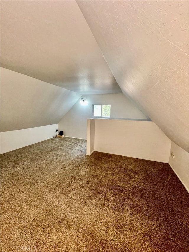 bonus room featuring carpet, a textured ceiling, and lofted ceiling