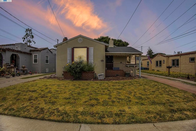 bungalow-style home featuring a lawn and covered porch