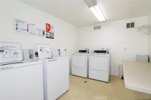 clothes washing area with light carpet and washer and dryer