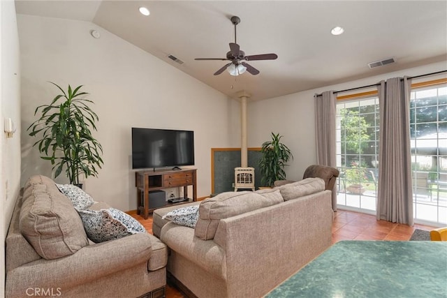 tiled living room with ceiling fan, vaulted ceiling, and a wood stove