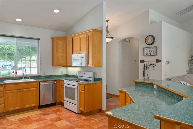 kitchen with pendant lighting, sink, white appliances, and vaulted ceiling