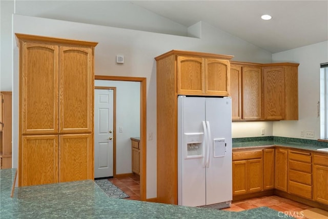 kitchen with light tile patterned flooring, vaulted ceiling, and white fridge with ice dispenser