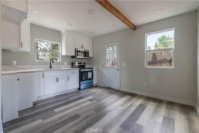 kitchen with baseboards, light wood-style flooring, appliances with stainless steel finishes, white cabinetry, and a sink