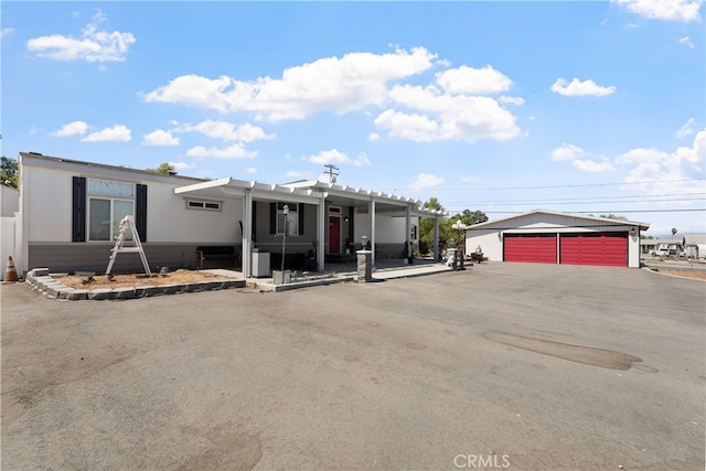 manufactured / mobile home with a garage, a pergola, and an outbuilding