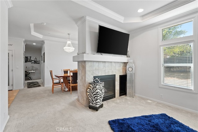 carpeted living room featuring a raised ceiling, plenty of natural light, a fireplace, and crown molding