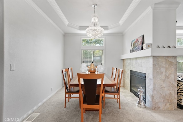 dining room featuring a healthy amount of sunlight, a tray ceiling, and a tiled fireplace