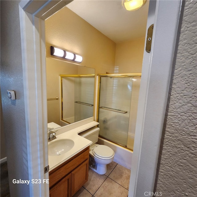 full bathroom featuring combined bath / shower with glass door, vanity, tile patterned floors, and toilet